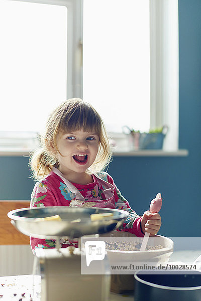 Lächelndes Mädchen beim Backen mit Rührschüssel in der Küche