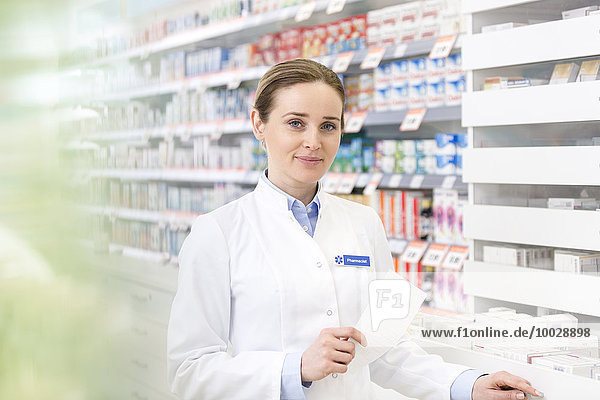 Portrait of confident pharmacist holding prescription in pharmacy