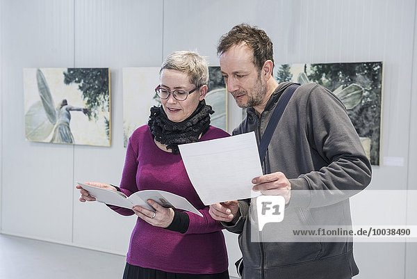 Visitors looking at brochures in an art gallery  Bavaria  Germany