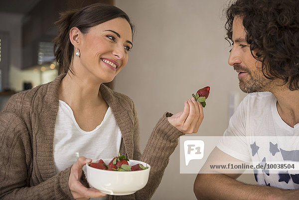 Mid adult woman feeding a strawberry to her husband  Munich  Bavaria  Germany