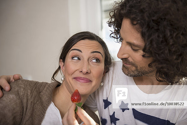 Mid adult man feeding a strawberry to his wife  Munich  Bavaria  Germany