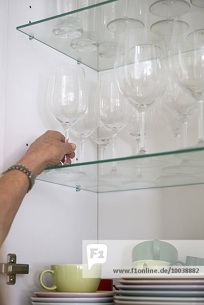 Close-up of a woman taking wineglass from cupboard  Munich  Bavaria  Germany