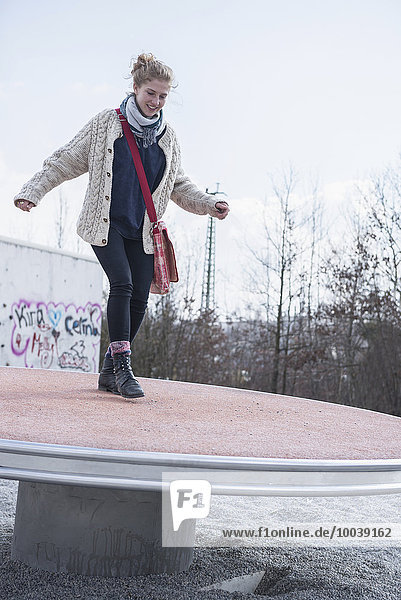 Young woman balancing on playground spinner  Munich  Bavaria  Germany
