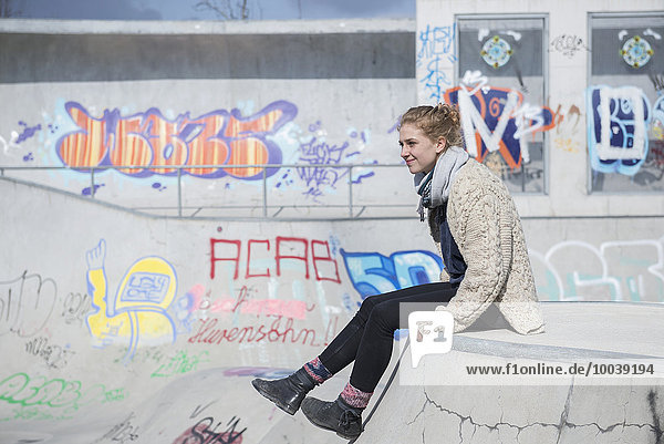Young woman sitting in skateboard park  Munich  Bavaria  Germany