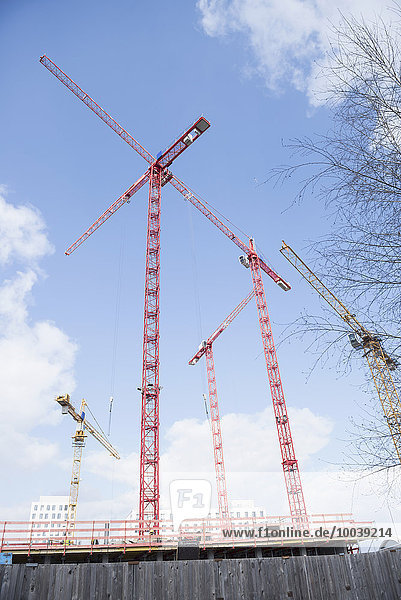 Low angle view of cranes at construction site cloudy sky  Munich  Bavaria  Germany