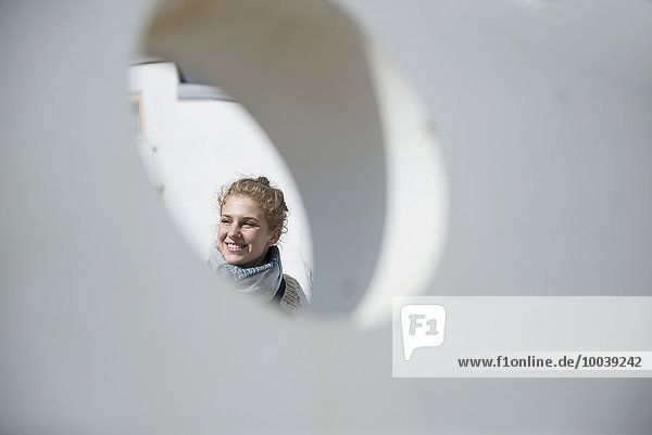 Young woman seen through a round hole in concrete wall  Munich  Bavaria  Germany