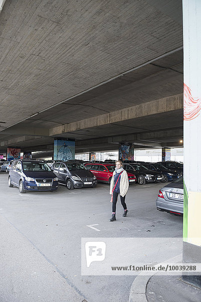 Young woman in a parking lot under a bridge made of concrete  Munich  Bavaria  Germany