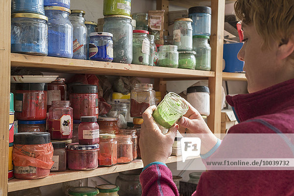 Female painter holding color bottle in art studio Bavaria Germany