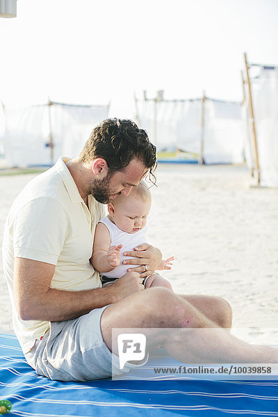 Father with baby relaxing on beach