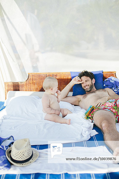 Father with baby relaxing on outdoor bed