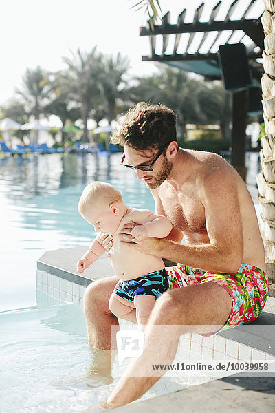 Father playing with baby boy at swimming-pool
