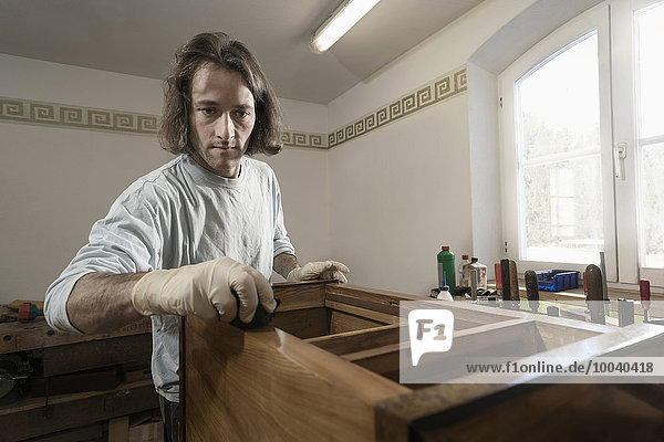 Carpenter French polishing on wooden drawer at workshop  Bavaria  Germany