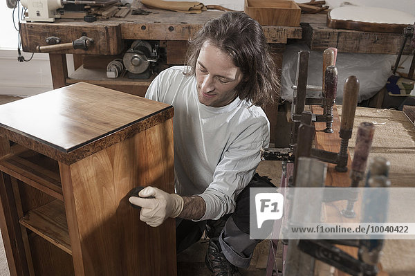 Carpenter French polishing wooden drawer at workshop  Bavaria  Germany