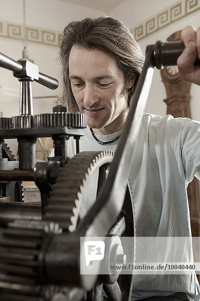 Restorer working on a sheet metal rolling mill at workshop  Bavaria  Germany