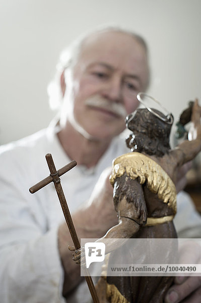 Senior sculptor works on a Jesus Christ statue at workshop  Bavaria  Germany