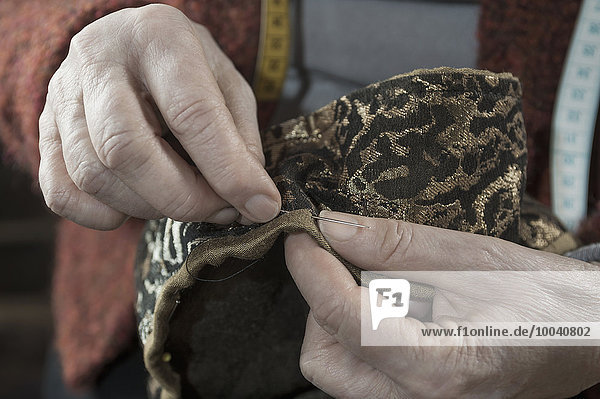Senior female fashion designer stitching in workshop  Bavaria  Germany