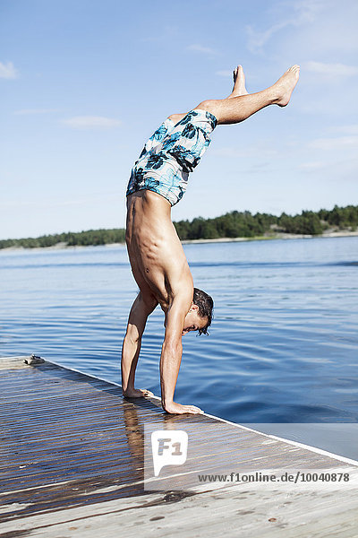 Teenage boy doing handstand on jetty
