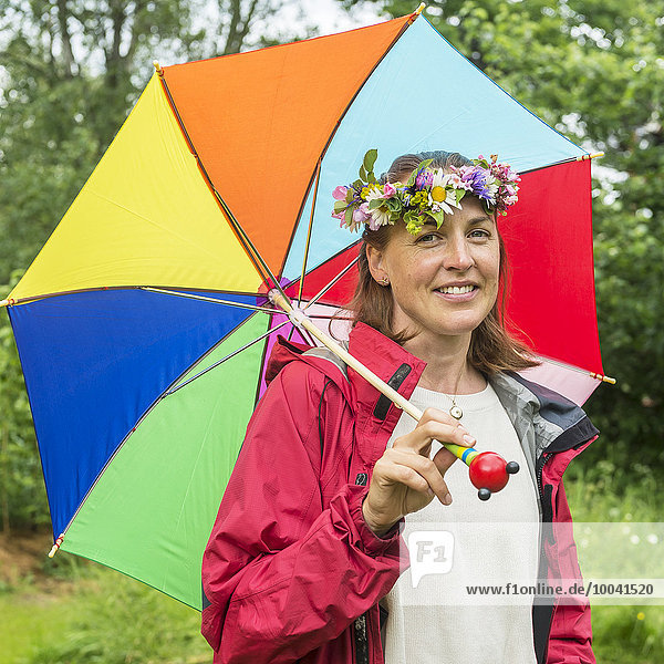 Smiling woman with flower wreath holding umbrella