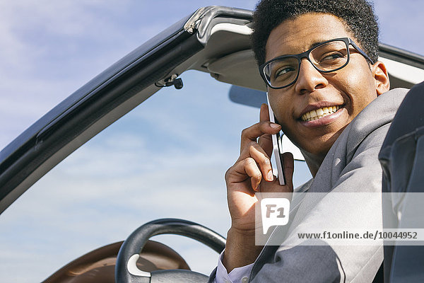 Young black man sitting in convertible  talking on the phone