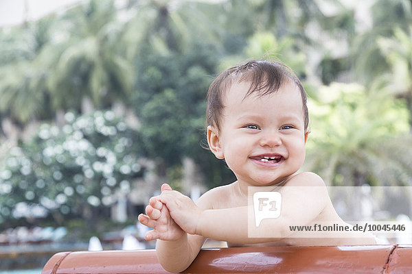 Lachendes kleines Mädchen auf Sonnenliege in Thailand