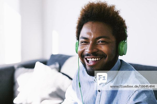 Young Afro American man wearing green headphones  laughing