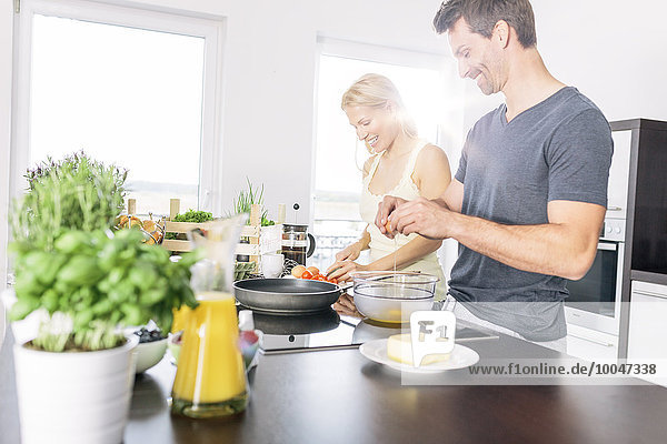 Couple preparing scrambled eggs together in the kitchen