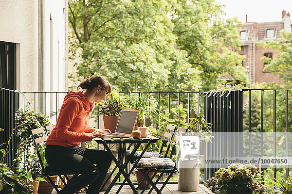 Woman using her laptop on balcony