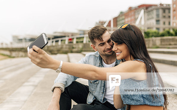 Spain  Gijon  young couple in love taking selfie with smartphone