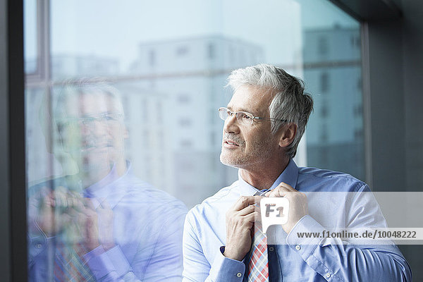 Businessman standing at window looking at distance