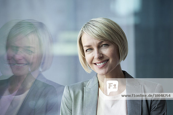 Geschäftsfrau am Fenster stehend  lächelnd  Portrait