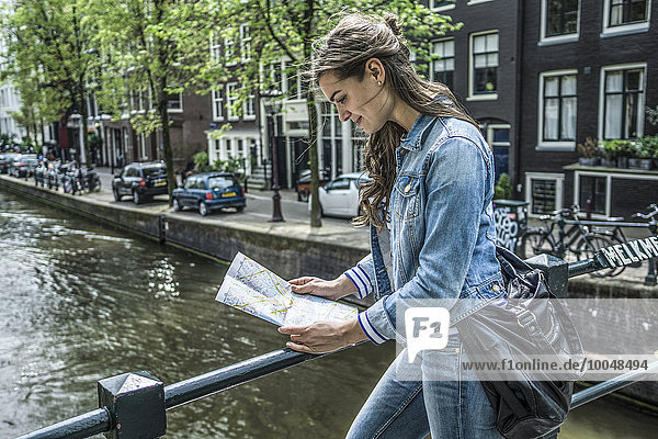 Niederlande,  Amsterdam,  Touristinnen beim Blick auf den Stadtplan vor dem Stadtkanal
