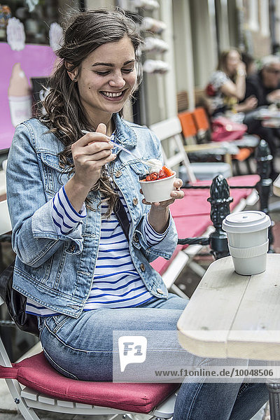 Netherlands  Amsterdam  female tourist sitting in a street cafe eating frozen yogurt