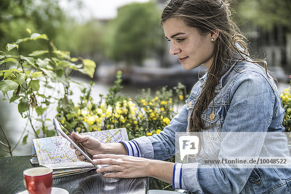 Niederlande  Amsterdam  Frau sitzt in einem Straßencafé mit digitalem Tablett