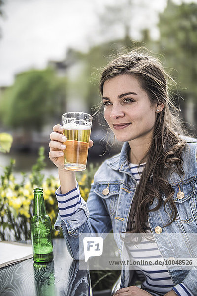 Niederlande  Amsterdam  Portrait einer Frau  die in einem Straßencafé ein Glas Bier trinkt.