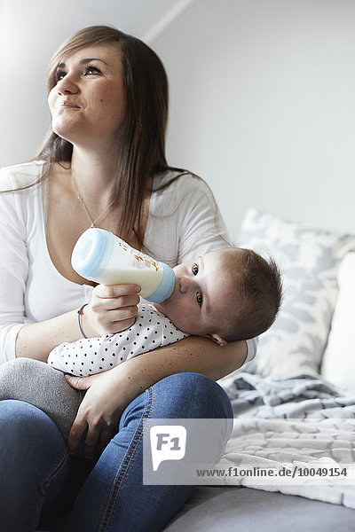 Young mother bottle-feeding baby at home