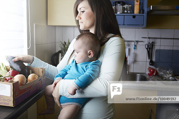 Junge Mutter hält Baby in der Küche
