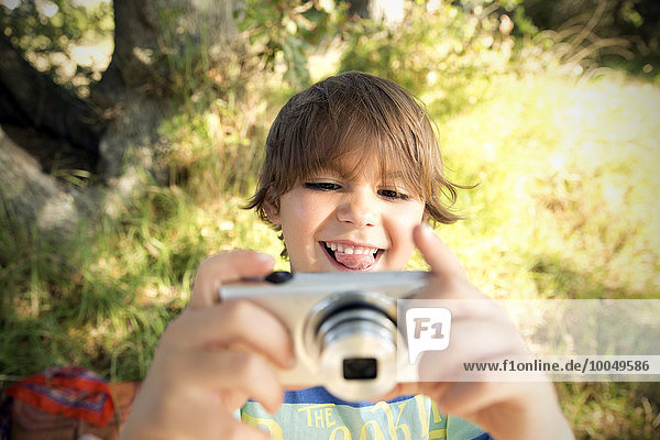 Smiling boy with camera outdoors