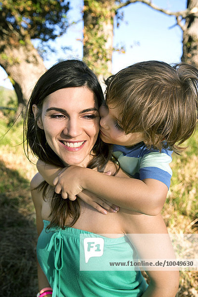 Glückliche Mutter mit Sohn Huckepack