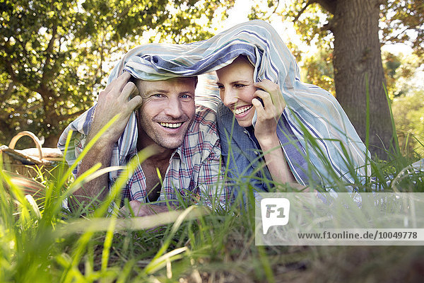 Glückliches Paar auf der Wiese unter einer Decke liegend