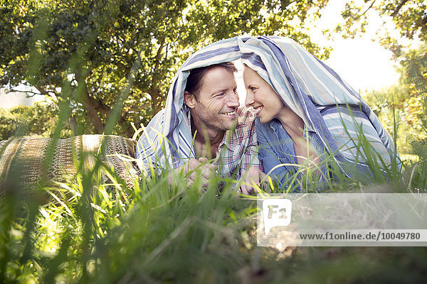 Glückliches Paar auf der Wiese unter einer Decke liegend