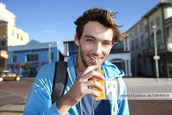 Portrait of smiling young man drinking from juice box