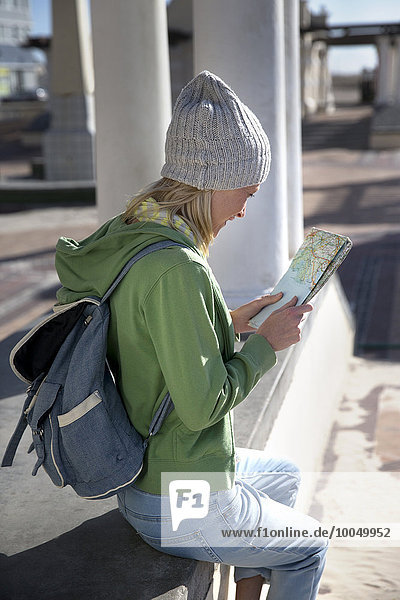Tourist sitting on promenade reading map