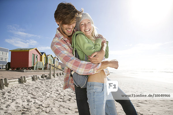 Verspieltes junges Paar am Strand