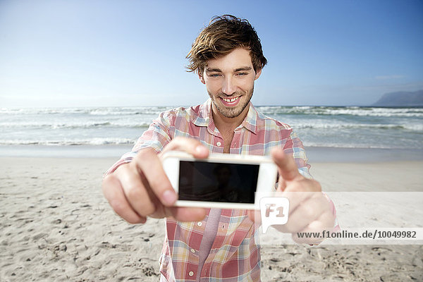 Junger Mann mit Selfie am Strand