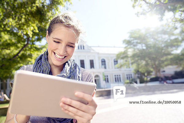 Glückliche junge Frau mit digitalem Tablett im Freien