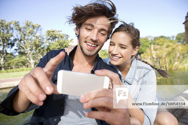 Glückliches junges Paar im Park mit einem Selfie