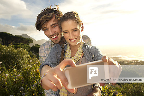 Ein glückliches junges Paar  das einen Selfie an der Küste nimmt.
