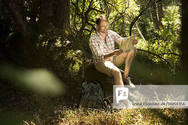 Wanderer sitzend auf Baumstamm Lesekarte