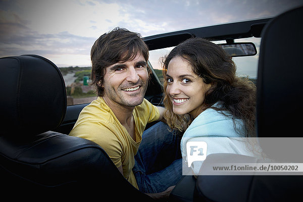 Südafrika  lächelndes Paar im Cabrio an der Küste bei Sonnenaufgang