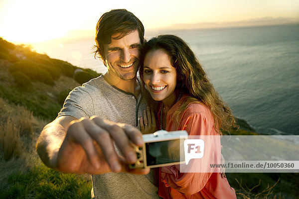 Südafrika  Paar  das bei Sonnenuntergang einen Selfie an der Küste nimmt